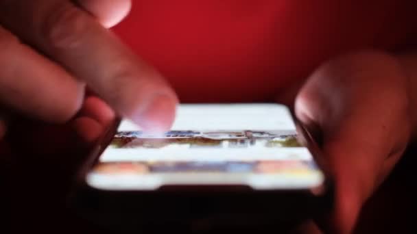 一个人正在使用便携式通讯设备 在黑暗中用手指在电子显示装置上做手势 用蓝色的电子字体点亮 — 图库视频影像