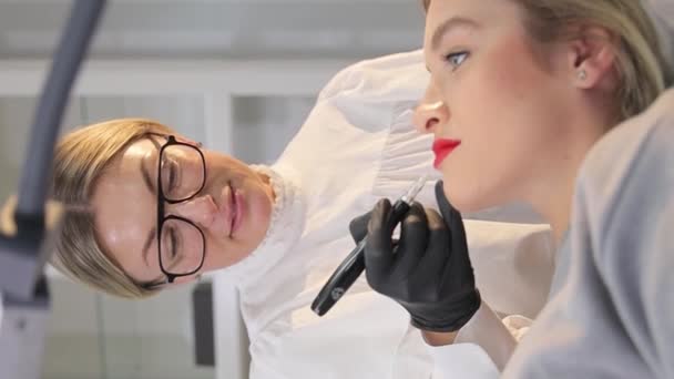 一个戴黑色手套的女性美容师用纹身机在女人的唇上做永久的妆容 微浸渍工艺 — 图库视频影像