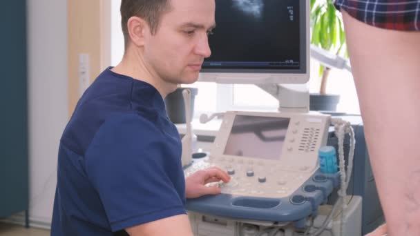 Ein Mann Bedient Ein Ultraschallgerät Einem Frauenbein Zur Medizinischen Auswertung — Stockvideo