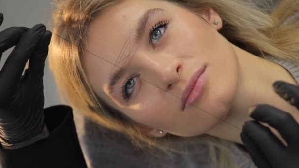 Menghapus Rambut Yang Tidak Diinginkan Dari Alis Dengan Benang Cosmetologist — Stok Video
