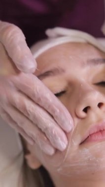 Genç bir kadın güzellik salonunda kozmetik cilt bakımı ve tedavi görüyor. Spa kozmetolojisi ve sağlık rahatlama konsepti. Cilt bakımı. Dikey video