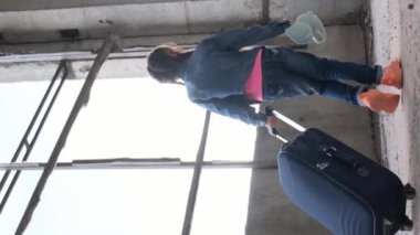 Miğfer takan genç bir kız, otomotiv lastiklerine mavi bir bavul takar, asfalt yollarda seyahat macerasının tadını çıkarır..