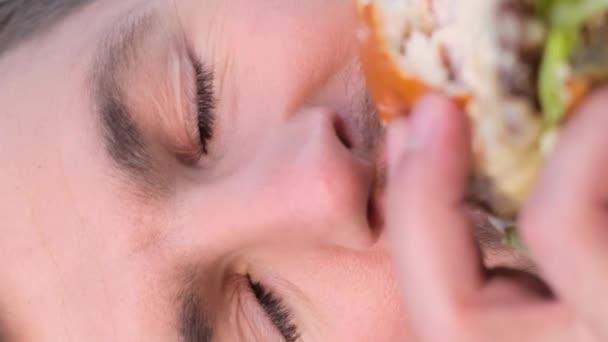 ひげ付きの男はハンバーガーを貯蓄し 目は閉じ 唇の味を味わい 歯の間のパンチを感じ 鼻で香りを楽しむ — ストック動画