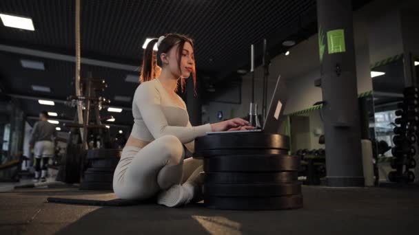 Kobieta Siedząca Podłodze Sali Gimnastycznej Używa Laptopa Rozrywki Gdy Gra — Wideo stockowe