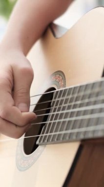 Birilerinin gitar, müzik aleti ve gitar telleri ve parmak hareketleriyle çalınan tellerin detaylı bir görüntüsü..