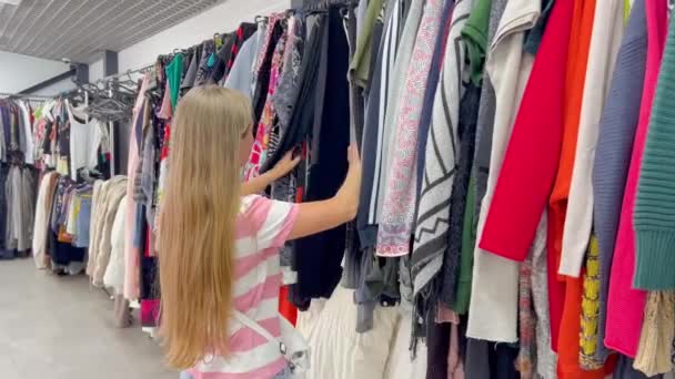 Kvinna Bläddrar Butik Undersöka Kläder Inklusive Magenta Shirts Med Olika — Stockvideo