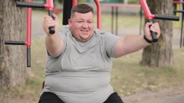 Толстый Молодой Человек Серой Футболке Делает Упражнения Тренажере Открытом Воздухе — стоковое видео
