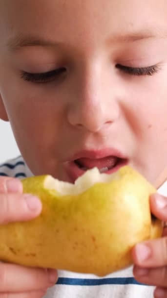 小男孩脸上挂着笑容 吃着梨子 露出咬痕 梨子靠近他的嘴 当他咬进去的时候 他的面颊微微鼓起 — 图库视频影像