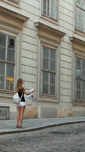 Kobieta Stoi Chodniku Badając Mapę Wpatrując Się Fasadę Budynków Otoczona — Wideo stockowe