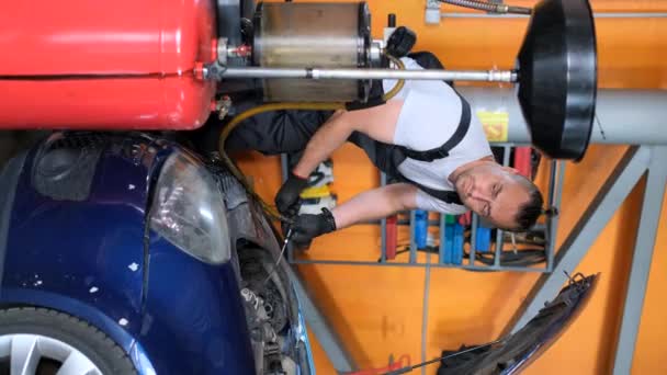 Mężczyzna Naprawia Pojazd Przebitą Oponą Garażu Pracując Nad Układem Kół — Wideo stockowe