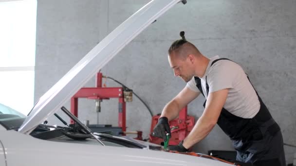 Mężczyzna Naprawia Samochód Garażu Maską Górze Otoczony Narzędziami Samochodowymi Elementami — Wideo stockowe