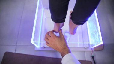 Bir doktor, insanların ayaklarını jest ve parmaklarıyla ölçer. Mor ayakkabıları için mükemmel bir uyum sağlar..
