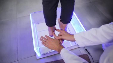 Resmi bir olayda, doktor bilek büyüklüğünde bir ölçüm aleti ve elektrikli mavi bir kol kullanarak insanların ayaklarını ölçer..