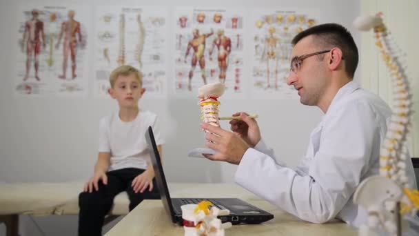 Doktor Bir Omurga Mankeni Tutarak Odada Genç Bir Çocukla Meşgul — Stok video