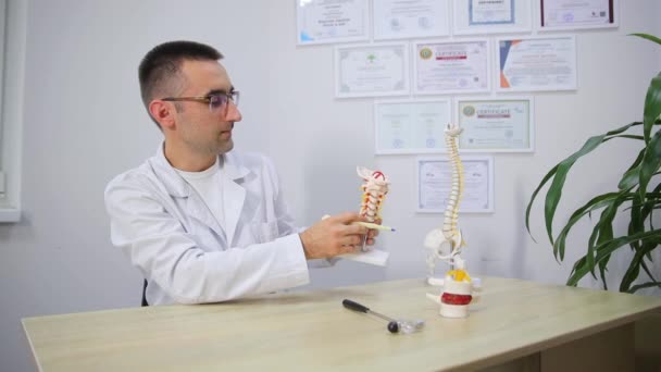 Médico Con Gafas Está Sentado Una Mesa Sosteniendo Modelo Columna — Vídeos de Stock