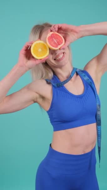 一个女人把几片瓦伦西亚橙放在眼前 脸上挂着微笑 当她用水果做一个有趣的手势时 她的胳膊肌肉扭动了 — 图库视频影像