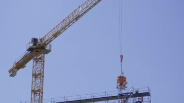 Gökyüzü yüksekliğinde bileşik malzemelerden yapılmış bir vinç, gelişmiş mühendislik teknikleriyle yapım aşamasında olan bir bina üzerinde etkili bir şekilde çalışıyor..