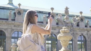 Bir kadın cep telefonuyla anıtsal bir binayı fotoğraflayarak şehrin mimarisinin güzelliğini yakalıyor..