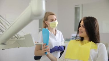 Bir kadın dişçi koltuğunda oturmuş dişçisiyle sohbet ederken musluktan su damlıyor..