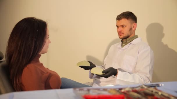 Uroczy Kompetentny Chirurg Plastyczny Pokazujący Swojemu Pacjentowi Implant Lekarz Oferuje — Wideo stockowe