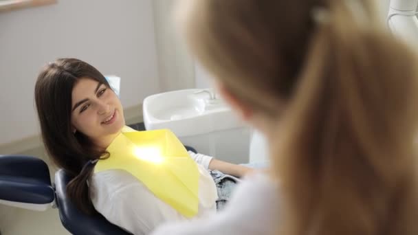 一个面带笑容的快乐女人正坐在牙椅上 与牙医讨论她的鼻子 下巴和睫毛 — 图库视频影像