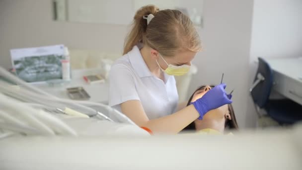 女性の歯科医が歯科オフィスのテーブルの患者歯を調べるために彼女の手を使用しています — ストック動画
