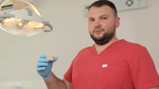 ひげのある歯科医が歯科オフィスで歯を握っています — ストック動画