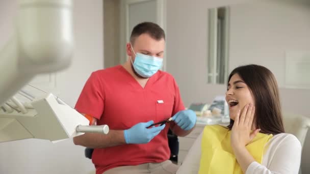 歯医者として歯の椅子に座っている女性は 筋肉をチェックするために手と指を使って歯を調べます — ストック動画