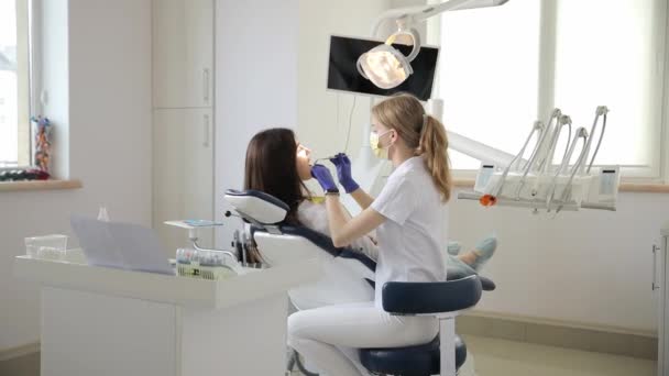 女性は テーブル 床のある部屋で歯科医と会話する歯科椅子に座っています 彼らの議論は 歯科サービスと彼女の重い不快感に焦点を当てています — ストック動画