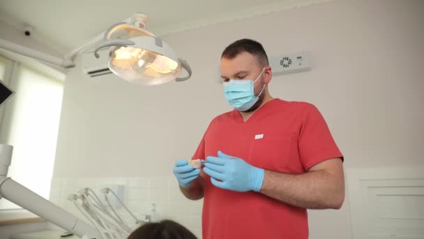 歯科オフィスでは マスクと手袋に飾られた歯科医が 最大限のケアとプロフェッショナリズムで患者歯を検査します — ストック動画