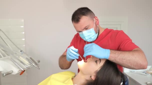 歯科医は あらゆる問題のために慎重に口の中を見るために手と腕を使用して 患者歯を検査しています 患者顎筋は検査中に観察することができる — ストック動画