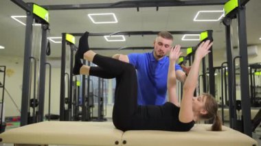 Bir erkek, fiziksel kondisyon için kol, diz, kalça ve bacak hareketlerine odaklanan masa egzersizlerinde bir kadına yardımcı olur..