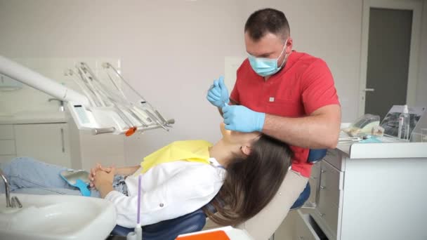 女性は歯科医によって歯科検査を受ける歯科椅子にあり 医療処置 歯科機器を使用しています — ストック動画