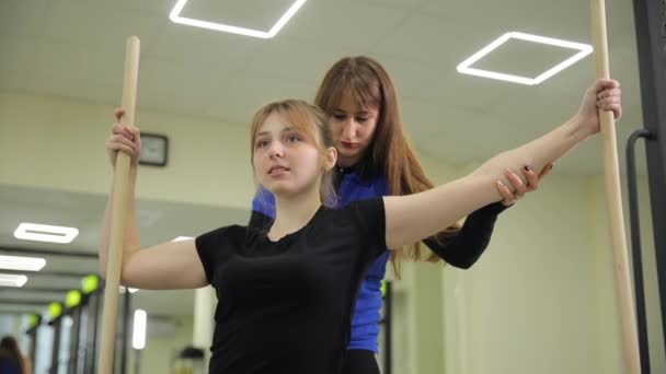 在体育馆里 一个女人正在用手势帮助一个伸臂的女孩达到她想要的动作 — 图库视频影像
