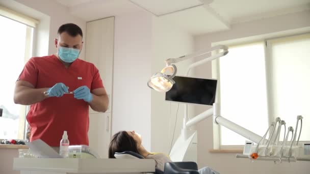 歯科医は 窓の景色 ハードウッドフローリング 天井の木材アクセントに焦点を当てたインテリアデザインの建物に位置する歯科オフィスで患者歯を調べています — ストック動画
