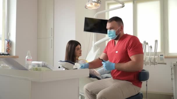 歯科医は 建物の歯科室に椅子とツールを使用して歯科オフィスで患者を診察しています — ストック動画