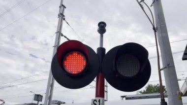 Demiryolu kavşağında kırmızı bir ışık parlıyor. Gökyüzü, ağaçlar ve bulutlar arasında canlı bir çember oluşturuyor..