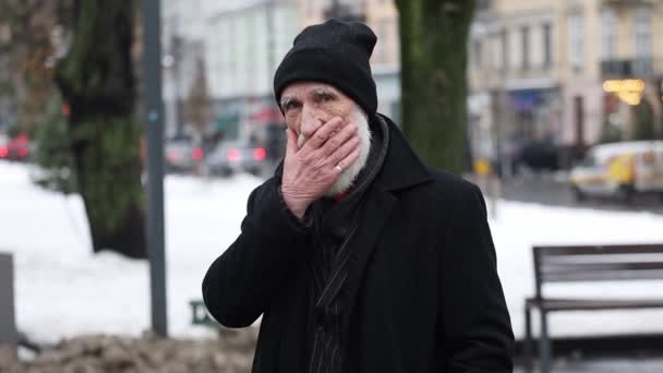 수염을 카메라를 주름을 수염된 남자의 초상화 도시의 배경에 코트에 긍정적인 — 비디오