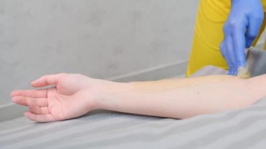 Birinin koluna yakın plan ağda yapılıyor, koluna, bileğine ve parmaklarına odaklanıyor..