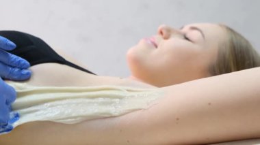 Kozmetik uzmanı koltuk altına wah macunu sürüyor. Yumuşak koltuk altı kavramı. Dişi koltuk altının rusk macunu kullanılarak dezenfekte edilmesi ve epilasyonu spatula olarak kullanılabilir..