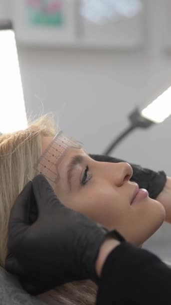 Kobieta Wytatuowane Brwi Salonie Siedząc Krześle Artysta Używa Sprzętu Audio — Wideo stockowe