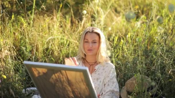 Kobieta Szczęśliwie Siedzi Trawie Malując Obraz Naturalnego Krajobrazu Otoczona Roślinami — Wideo stockowe