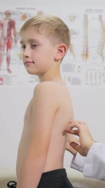 Ortopedist randevusunda bir genç. Profesyonel bir ortopedist bir çocuğu muayene eder. Okul çocuklarında omurga eğriliğinin önlenmesi
