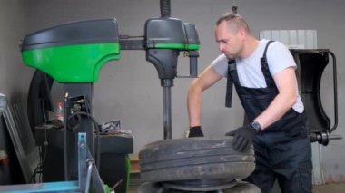 Otomotiv lastiğini garajdaki bir makineye takan bir adam mühendislik ve mekanik serviste uzmanlığını gösteriyor..