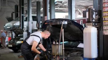 Bir adam garajda bir aracı tamir ediyor, otomotiv lastikleri, tekerlekler ve aracın dış yüzeyi üzerinde çalışıyor mühendislik aletleri ve ahşap malzemelerle..
