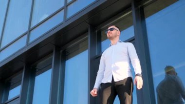 Resmi giyinmiş bir adam gözlerini kaçırıyor, ellerini sallıyor. Ofis çalışanı ofisin yanındaki sokakta..