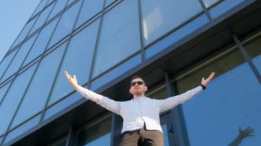 Kollarını açıp binanın önünde duran bir adam, bir ofis çalışanı. Özgürlük kavramı.