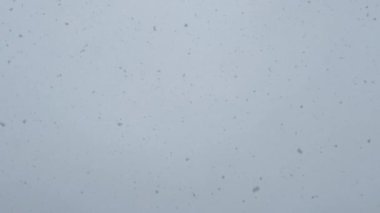 Gökyüzündeki donmuş su kristallerine benzeyen el değmemiş beyaz bir yüzeye inen kar tanelerinin detaylı bir görüntüsü.