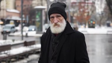 Şehirde dikilip kameraya bakan buruşuk sakallı yaşlı bir adamın portresi. Düşünceli, üzgün, yaşlı, yalnız dede..