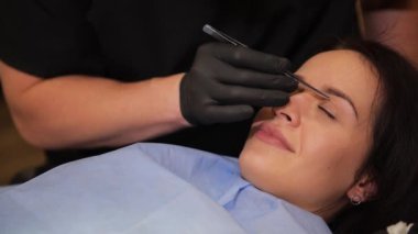 Doktor kadının yüzünü kontrol ediyor, estetik ameliyattan önceki göz kapağı, biberoplasti. Cerrah ya da güzellik uzmanı elleri kadın yüzüne dokunuyor..